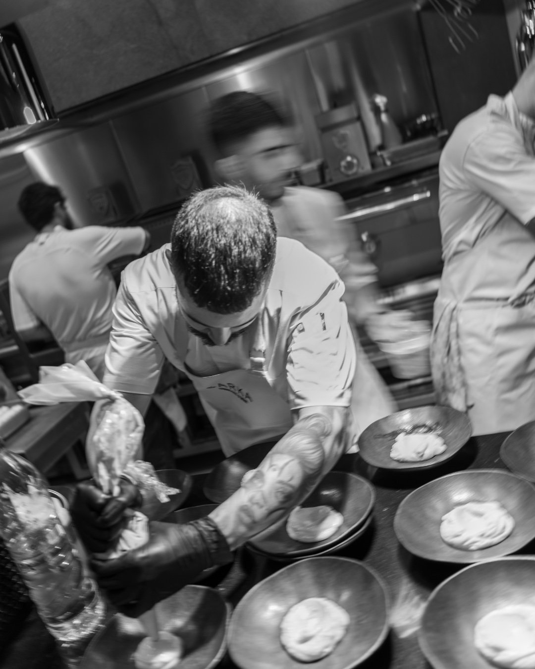 Black-and-white shot of a chef plating in the SÁRKA kitchen