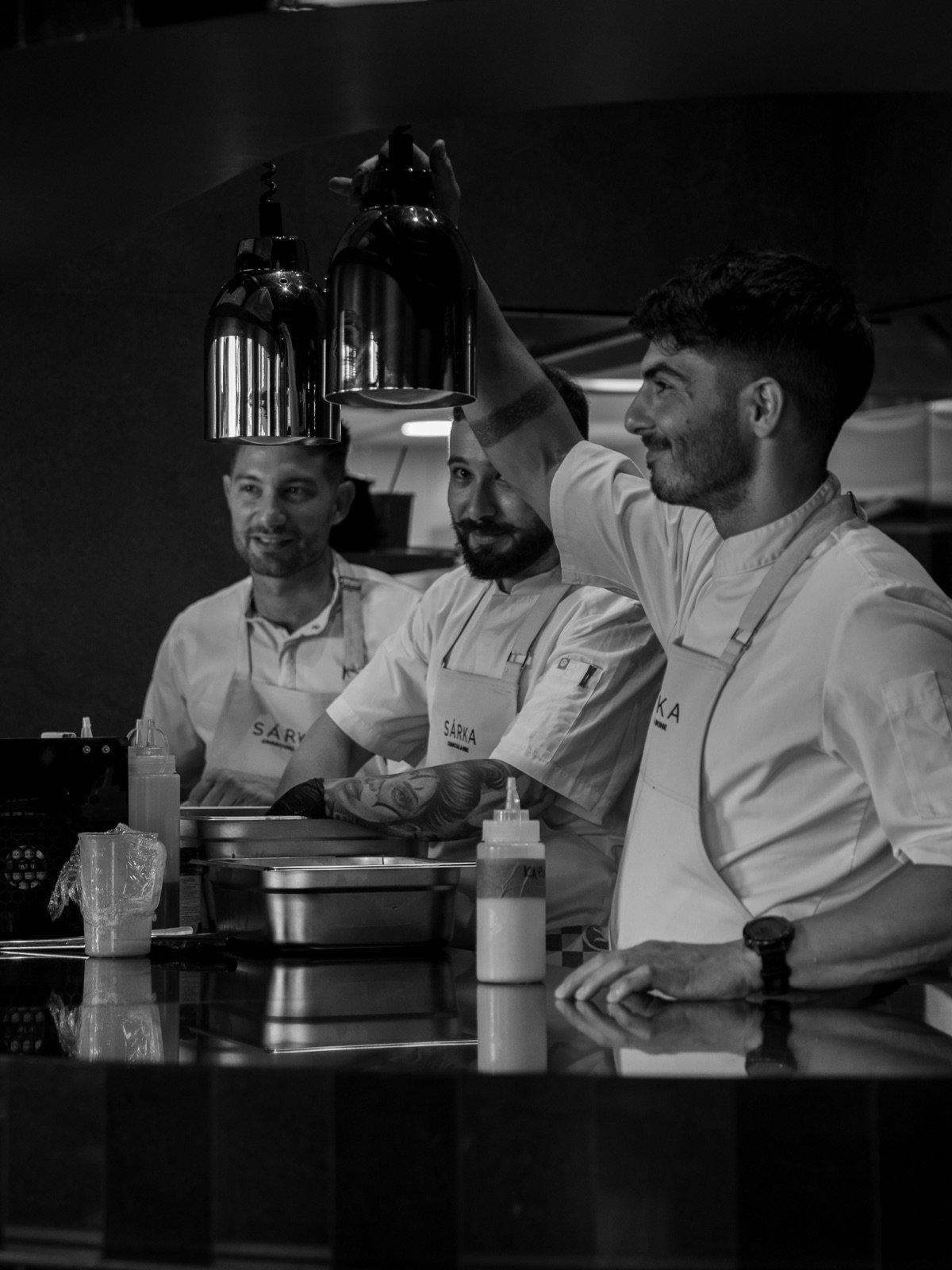 Black-and-white shot of the kitchen team laughing during service