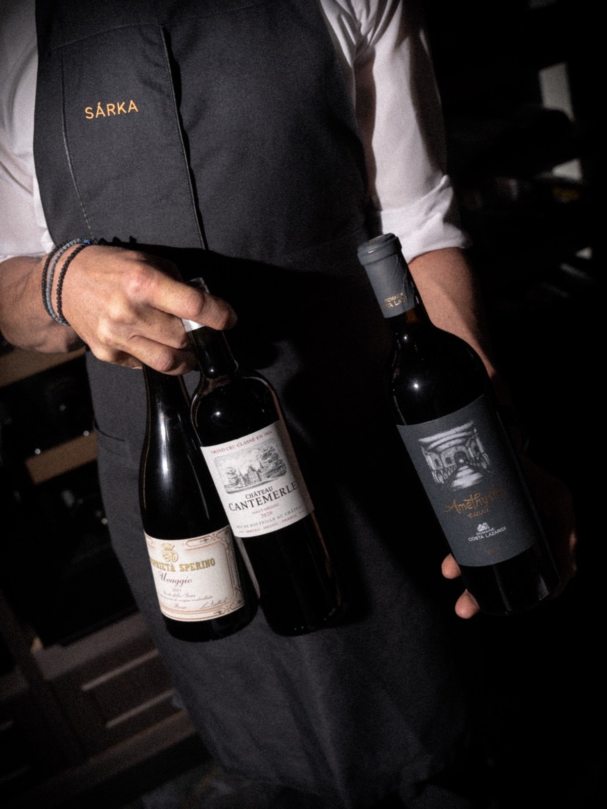 Waiter in a SÁRKA apron presenting bottles of wine