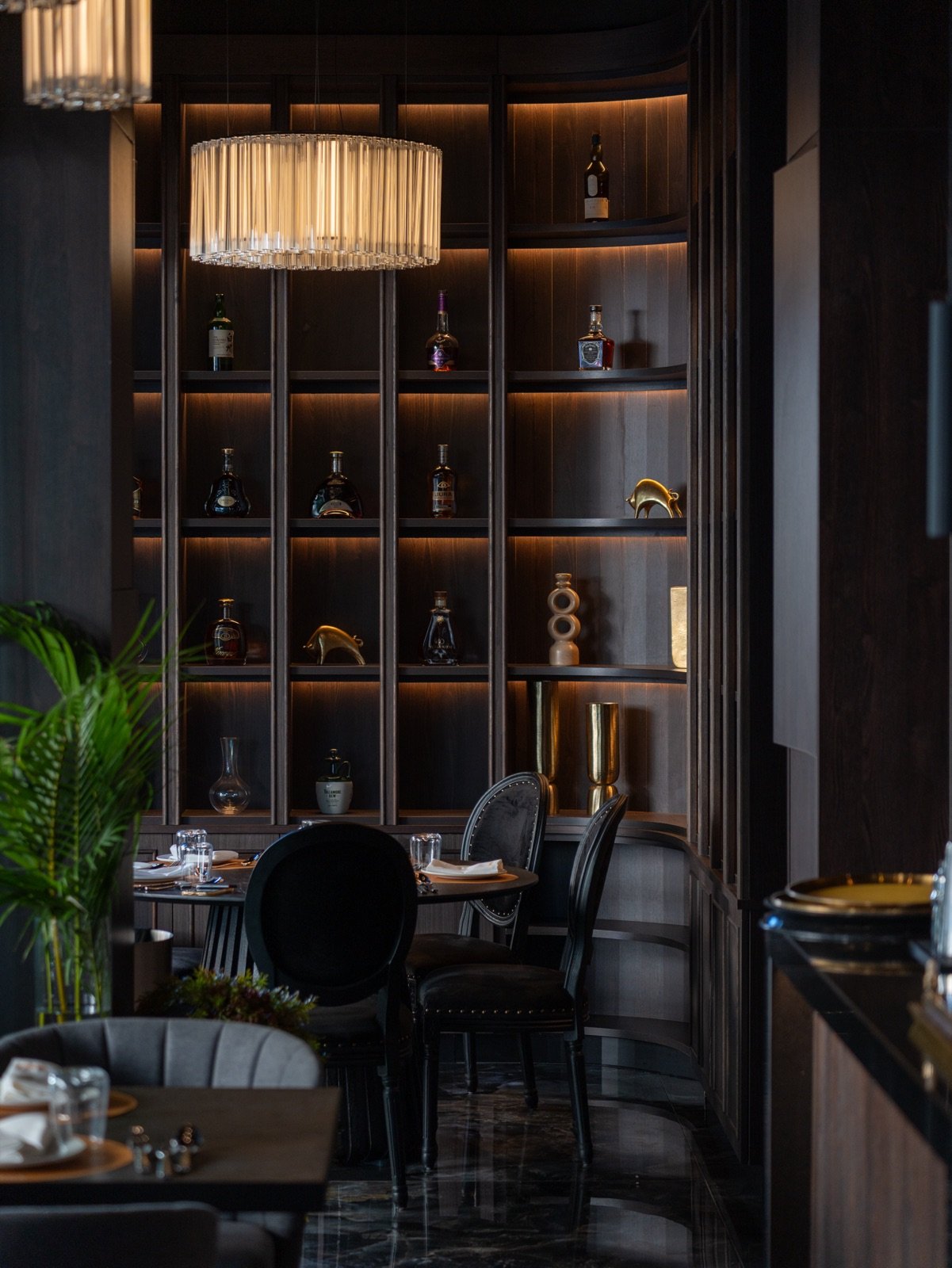 The SÁRKA dining room with a chandelier and backlit shelves